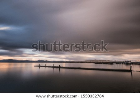 Long exposure view of a pier on a lake, with moving clouds and still water