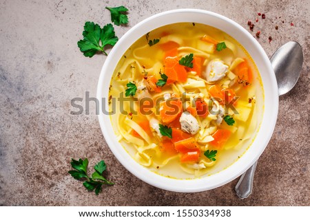 Chicken noodle soup with parsley and vegetables in a white plate, gray background. Royalty-Free Stock Photo #1550334938