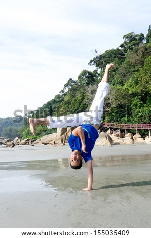 Acrobatic action of capoeira instructor on the beach. Seen in the picture, motion blur on the feet because of acrobatic movements