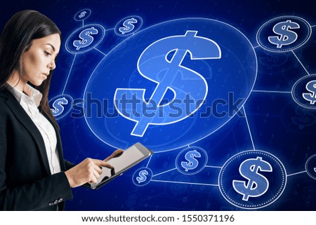 Attractive european businesswoman using tablet with creative glowing blue dollar icon interface hud on dark blurry background. Cryptocurrency and technology concept 