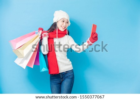 asian woman wear winter clothes and take selfie isolated on blue background