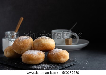 Homemade deep fried sweet fritters covered with sugar on a dark background
