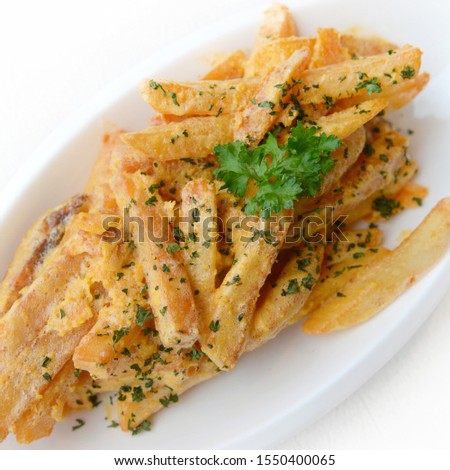 French fries seasoned with Salted Egg on the white plate on white background. fusion food concept.selective focus.
