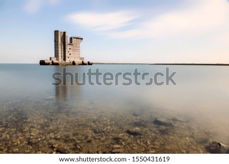 A high rise building reflected in the sea under the beautiful cloudy sky