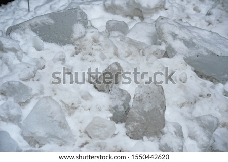 Pile of snow with pieces of ice is close