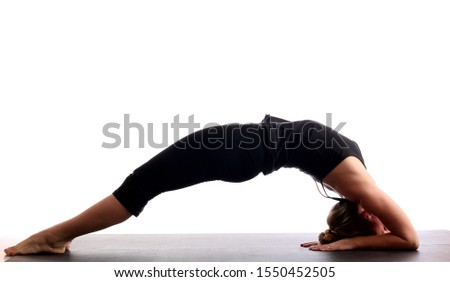 Young beautiful yoga female posing on a studio background. Standing in pose of an inverted staff, Dvipada Viparita Dundasana. Healthy and active lifestyle.