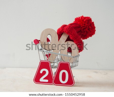 Winter sale and shopping concept. Red knitted hat and scarf with wooden sign percent over white background