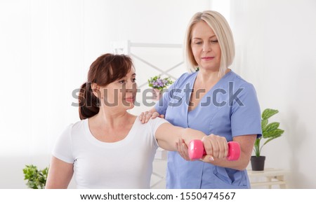 Picture of middle aged woman during rehabilitation in professional clinic. Rehabilitation, physiotherapy with dumbbells closeup. Restoration, rehabilitation, after an injury,