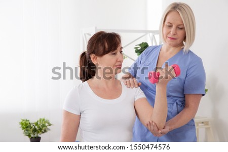 Picture of middle aged woman during rehabilitation in professional clinic. Rehabilitation, physiotherapy with dumbbells closeup. Restoration, rehabilitation, after an injury,