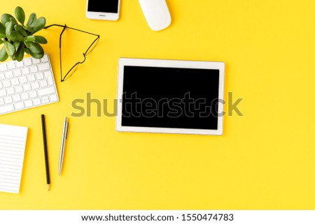 Digital tablet with empty screen on yellow background with business accessories. Office desktop