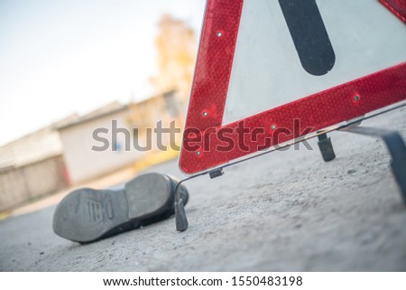 An accident on the road involving a person. Close up of a man's boot and an emergency stop sign Red triangle