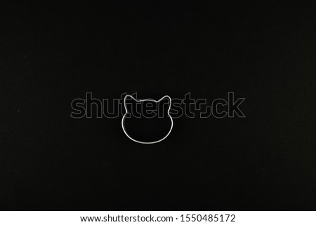Cat logo on a black background. Cat head logo. Abstract logo with a cat's head in black and white. Metallic cat mould for biscuits.