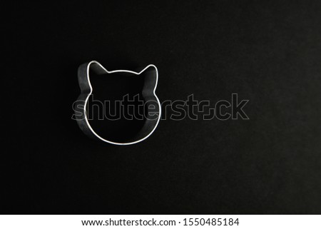 Cat logo on a black background. Cat head logo. Abstract logo with a cat's head in black and white. Metallic cat mould for biscuits.