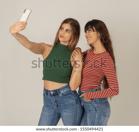 Two beautiful happy girlfriends taking selfies or recording video for blog on social media. Selfie of two beautiful women together having fun. People, technology, friendship and social media concept.