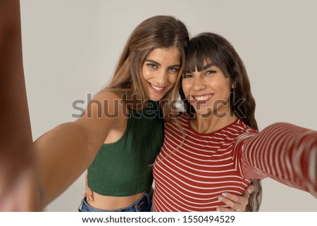Two beautiful happy girlfriends taking selfies or recording video for blog on social media. Selfie of two beautiful women together having fun. People, technology, friendship and social media concept.
