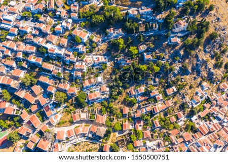 Aerial drone bird's eye view shot of scenic small town and Harbor with ships and yachts traditional Greek style white houses and the seaport with docked boats, island
