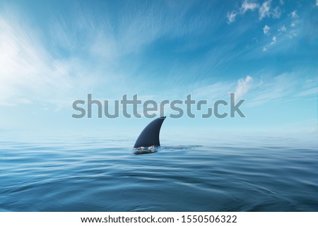 shark fin on surface of ocean agains blue cloudy sky Royalty-Free Stock Photo #1550506322