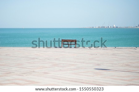 An empty chair along the Corniche or the boardwalk overlooking the sea or the bay in Doha Qatar Royalty-Free Stock Photo #1550550323