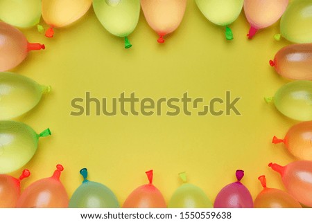 frame of multi color water balloons on yellow background 