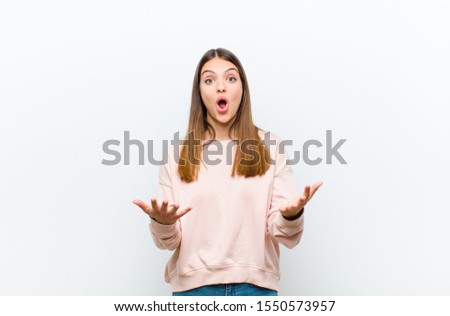 young pretty woman open-mouthed and amazed, shocked and astonished with an unbelievable surprise against white background