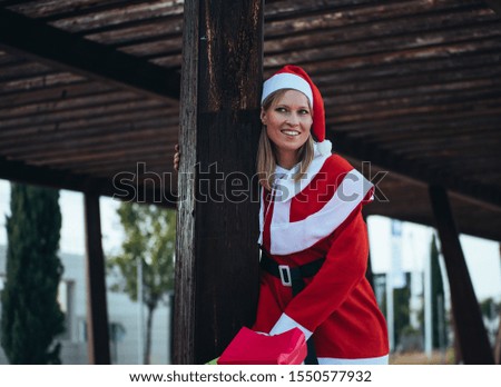 Stock photo of mama noel leaned on a wooden pole with expression of happiness. Christmas time