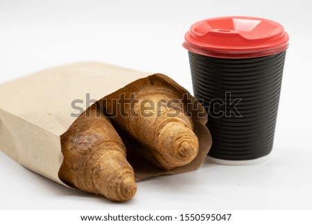 Coffee in a paper cup and a croissant on a light background. The concept of fast food and coffee to go.