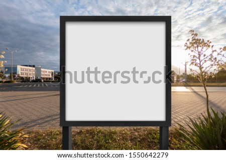 Mockup of the blank white street city outdoor advertising square billboard in black frame on sidewalk