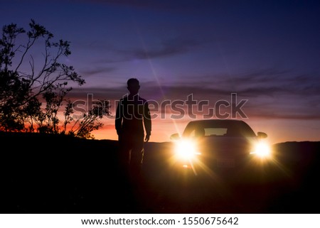 a man who stand by the car for looking the sky when the sunset