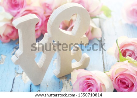 The Word "Love" In Wood With Pink Roses On A Blue Background