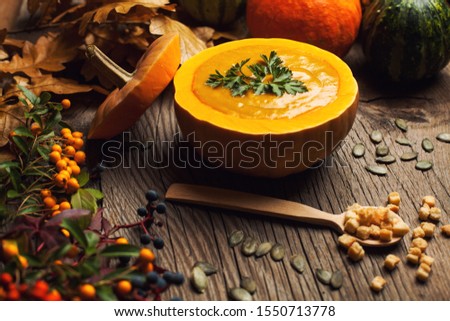 Roasted butternut squash or pumpkin soup, home made Thanksgiving dish served in a carved pumpkin, warm cozy homely hygge mood and atmosphere  