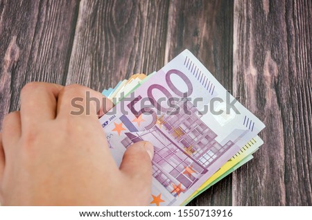 hand takes 500 euros on a wooden background, close-up.