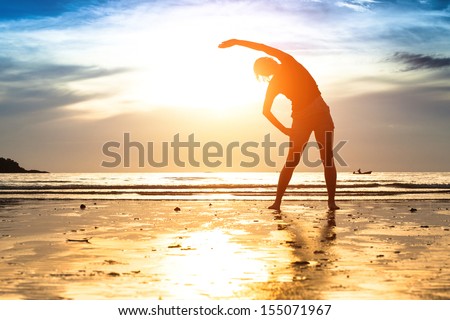 Silhouette young woman, exercise on the beach at sunset
