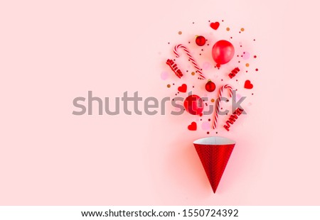 Red box with confetti, balloons, streamers and decoration on a pink background. Colorful celebration, birthday background. Flat lay, top view 