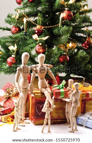 Decorated Christmas tree (artificial) surrounded by wrapped presents and family of jointed mannequins exchanging gifts