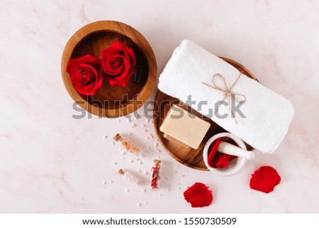 Spa product with rose oil and 
Rose petals on pink marble background.