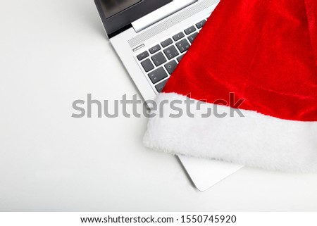 Laptop on a white isolated background. A hat of santaclaus lies on a laptop. The end of the working year. Holiday sales.