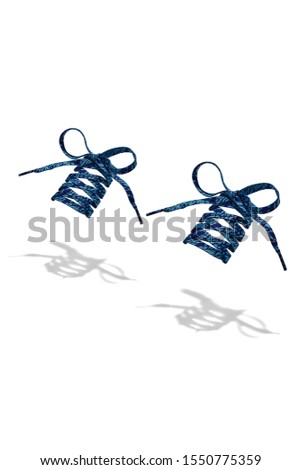 The photo of dark blue wicker shoelaces with blue abstract print and blue tips, hanging in the air on a white background. Shoelaces is casting a shadow. 