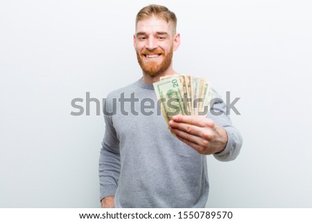 young red head man with dollars against white background