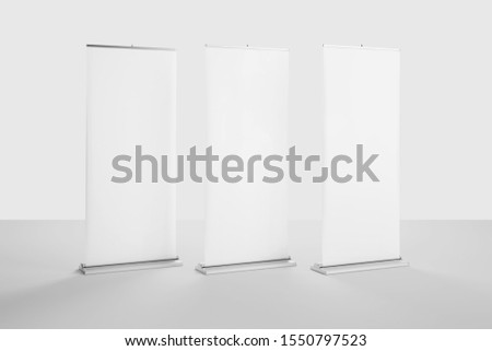 Mockup of white blank roll up banners template standing in bright clean studio against the wall