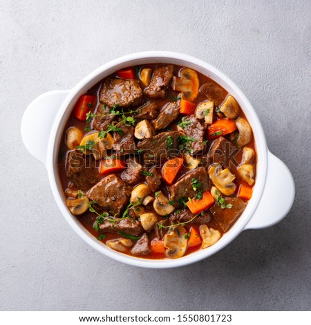 Beef bourguignon stew with vegetables. Grey background. Top view. Royalty-Free Stock Photo #1550801723