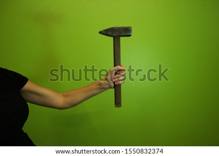 Closeup of woman hand with a hammer isolated on green background