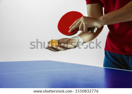 Young man plays table tennis on white studio background. Model in sportwear plays ping pong. Concept of leisure activity, sport, human emotions in gameplay, healthy lifestyle, motion, action, movement
