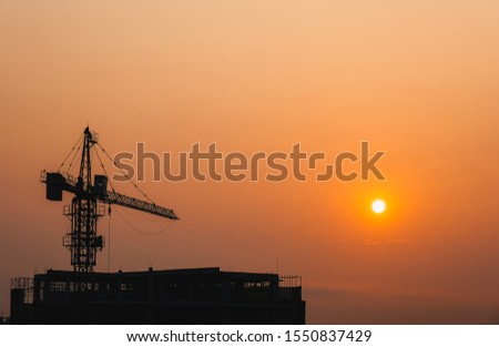 Crane building construction site at sunset or sunrise. High-quality stock photo image silhouette of construction tower crane in sunset sky background. Building construction with crane during sunset