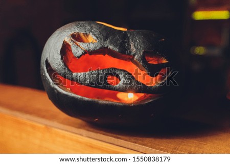 Halloween pumpkin lantern with dry leaves with black background.