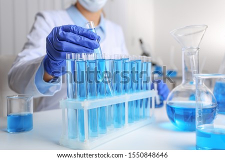 Doctor taking test tube with blue liquid, closeup. Laboratory analysis Royalty-Free Stock Photo #1550848646