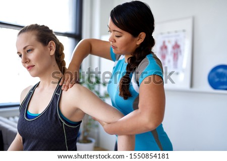 Candid image of an attractive patient during a appointment with professional asian physiotherapist in design kinesio clinic working and massaging her neck and shoulder pain Royalty-Free Stock Photo #1550854181