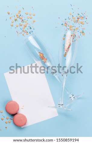 Champagne glasses and colorful sweets holiday template. Christmas, Birthday or Valentines'day over blue background. Top view with space for your greetings. Flat lay