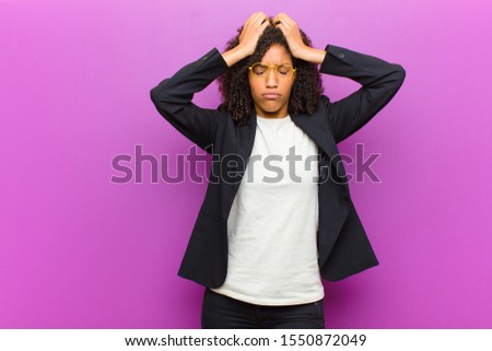young black business woman feeling stressed and anxious, depressed and frustrated with a headache, raising both hands to head