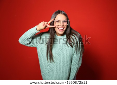 Young woman in warm sweater on red background