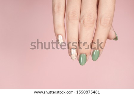 Closeup top view of beautiful hand of white woman isolated on pink pastel background. Fingernails with stylish trendy two colors faded manicure made with modern gel polish and silver stamping design.